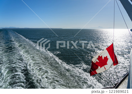 Ferry sailing on the ocean. Canadian flag and waves. Southern Gulf Islands, Strait of Georgia. Ferry sailing on the ocean. Canadian flag and waves. Southern Gulf Islands, Strait of Georgia. 121989021