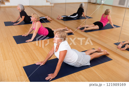 Senior woman doing Urdhva Mukha Shvanasana during group yoga workout 121989169
