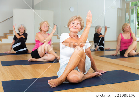 Smiling senior woman sitting in twisting asana Matsyendrasana 121989176