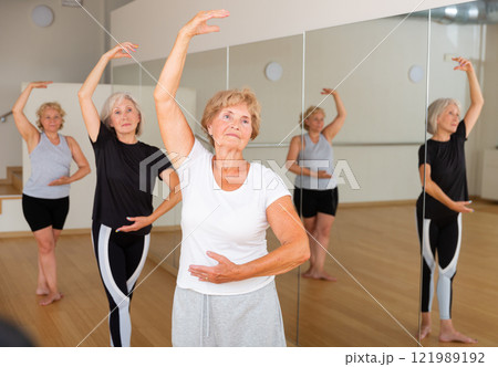 Mature women stand in the 4th position of the ballet stand in the dance studio Mature women stand in the 4th position of the ballet stand in the dance studio 121989192