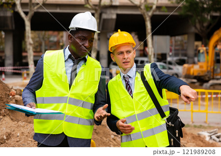 Engineers discussing road mending outdoors Engineers discussing road mending outdoors 121989208