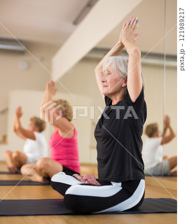 Mature woman making yoga meditation in lotus pose in fitness center Mature woman making yoga meditation in lotus pose in fitness center 121989217