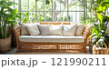 A beautiful indoor rattan couch surrounded by lush green plants creates a calming atmosphere. This cozy seating adds warmth to any space. Perfect for relaxation or social gatherings. AI 121990211