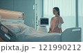 A woman stands by a hospital bed in a serene medical environment. Soft light creates a calming atmosphere. The scene captures a moment of reflection and care in healthcare settings. AI 121990212