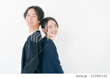 背中を合わせて微笑む若い男女 121991142