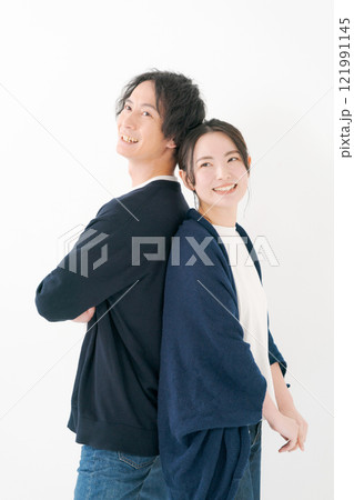 背中を合わせて微笑む若い男女 121991145