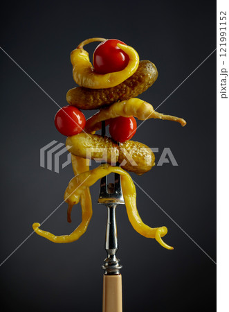 Canned yellow peppers, cucumbers, and tomatoes on a black background. 121991152