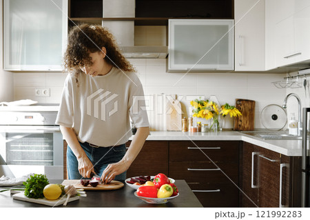 Woman cutting an onion into quarters while preparing lunch 121992283