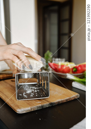 Unrecognizable woman grating cheese 121992290
