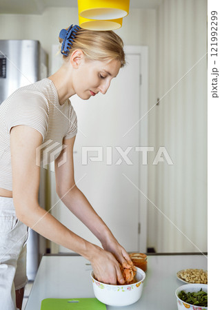 Woman preparing a meal by mixing ingredients in a bowl in a modern kitchen during the day Woman preparing a meal by mixing ingredients in a bowl in a modern kitchen during the day 121992299