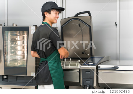 厨房でフライヤーを使う調理スタッフの男性 厨房でフライヤーを使う調理スタッフの男性 121992456