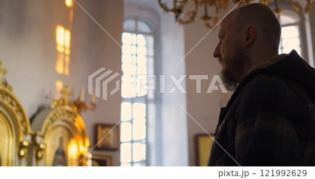 Christian Man crosses himself while praying in serene church ambiance filled with tranquility enhances spirituality and offers unique religious experience, meditation and peace. Faith in God concept 121992629