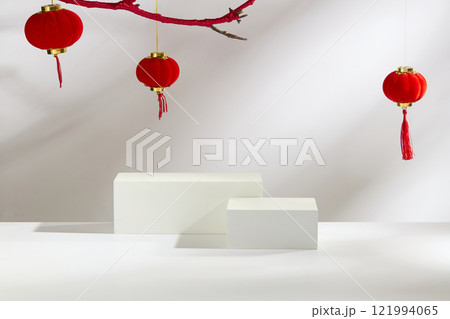 Some empty white rectangular podium for showcasing products. Decorated by Chinese lanterns, it hangs on a red branch, a red plate of mandarin oranges on a white background. Lunar New Year concept. Some empty white rectangular podium for showcasing products. Decorated by Chinese lanterns, it hangs on a red branch, a red plate of mandarin oranges on a white background. Lunar New Year concept. 121994065