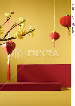 An idea for Lunar New Year. Frontal view of two red cylindrical pedestals for showing a product against a golden backdrop. Chinese lanterns with red and yellow apricot blossoms as decorations. 121994091