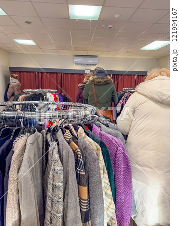 Thrift store shoppers browse racks of clothing. High quality photo 121994167