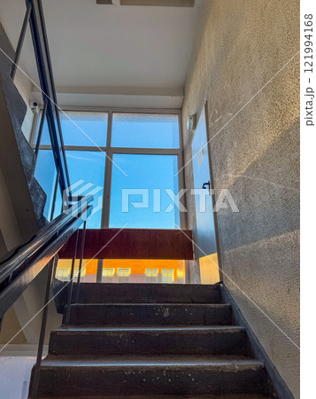 well-lit concrete staircase with a handrail and a window overlooking a clear sky. High quality photo 121994168