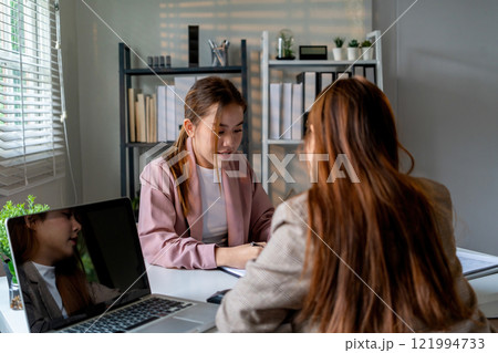 Businesswoman sitting at desk on couch in workplace or at home working on laptop and analyzing data on charts and graphs and writing on papers to make business plan and strategies for company 121994733