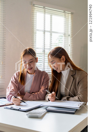 Businesswoman sitting at desk on couch in workplace or at home working on laptop and analyzing data on charts and graphs and writing on papers to make business plan and strategies for company 121994740