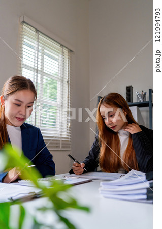 Businesswoman sitting at desk on couch in workplace or at home working on laptop and analyzing data on charts and graphs and writing on papers to make business plan and strategies for company Businesswoman sitting at desk on couch in workplace or at home working on laptop and analyzing data on charts and graphs and writing on papers to make business plan and strategies for company 121994793