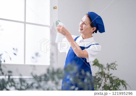 窓を掃除するシニア女性のハウスキーパー 121995296