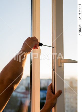 Hand of worker adjusting plastic window. Hand of worker adjusting plastic window. 121996421