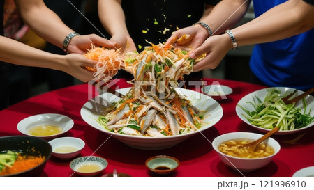 Hands tossing vibrant Asian salad for celebration 121996910