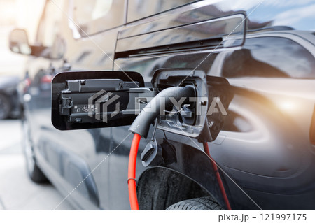 Close-up modern electric plug-in hybrid car van parked near fast charger charging station point center street old European city. Eco friendly green energy vehicle. Zero emission transport technology 121997175
