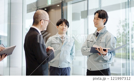 ロビーで話をするビジネスマンと作業服を着た男性 ロビーで話をするビジネスマンと作業服を着た男性 121997312