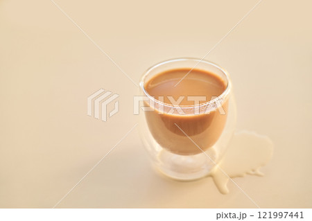 Double walled glass cup with spilled coffee on light beige surface 121997441