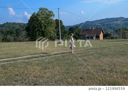 Woman with a summer hat is watching a countryside landscape in summertime Woman with a summer hat is watching a countryside landscape in summertime 121998559