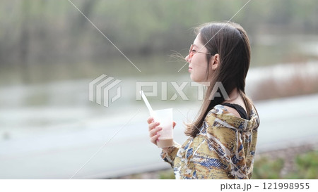 Pensive happy woman sipping a milkshake in the street Pensive happy woman sipping a milkshake in the street 121998955