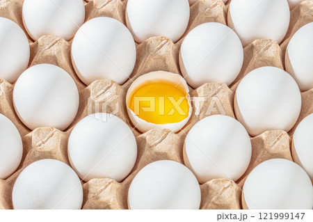 Row of white eggs and single broken egg with a yolk. White Eggs and Yellow Egg Yolk. Individuality and difference concept Row of white eggs and single broken egg with a yolk. White Eggs and Yellow Egg Yolk. Individuality and difference concept 121999147
