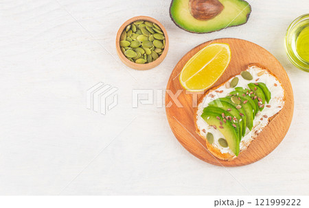Avocado toasts with cream cheese and seeds on white table background, top view 121999222