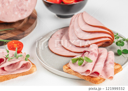 Plate of tasty sandwiches with boiled sausage and tomato on white table Plate of tasty sandwiches with boiled sausage and tomato on white table 121999332