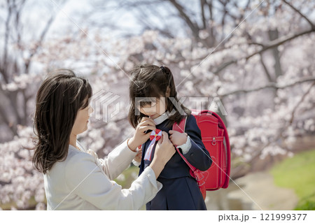 桜の咲く公園でランドセル姿の娘にリボンをつける母親 桜の咲く公園でランドセル姿の娘にリボンをつける母親 121999377