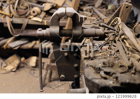 Vintage metal vise in a cluttered workshop 121999628