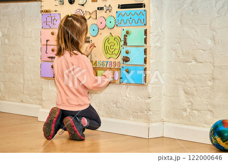 Cute child in kindergarten makes up different shapes on the wall board Cute child in kindergarten makes up different shapes on the wall board 122000646