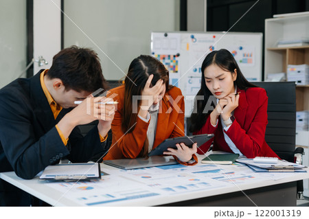Businessman team working are under stress from financial data and report graph. Businessman team working are under stress from financial data and report graph. 122001319