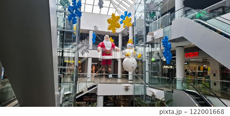 New Year's decorations in a hypermarket. New Year's models of Santa Claus and a snowman are suspended at the top of the hypermarket's hall. New Year's decorations in a hypermarket. New Year's models of Santa Claus and a snowman are suspended at the top of the hypermarket's hall. 122001668