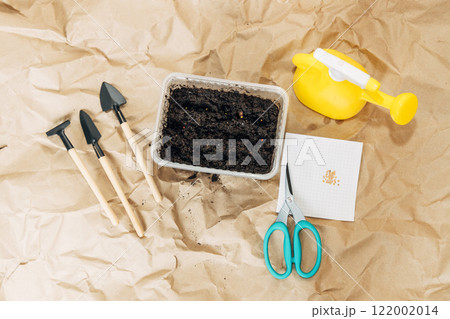 Kraft paper background, fertile soil and garden tools on top, top view. Planting seedlings in spring Kraft paper background, fertile soil and garden tools on top, top view. Planting seedlings in spring 122002014