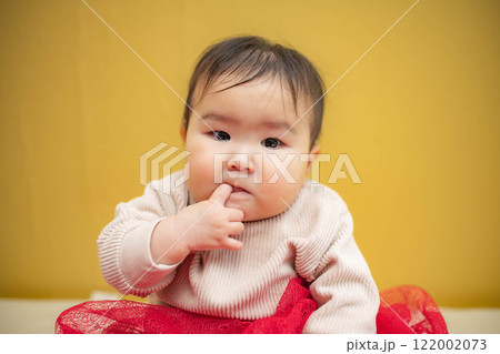 黄色バックでお座りしている涙目の赤ちゃん 黄色バックでお座りしている涙目の赤ちゃん 122002073