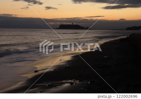 鎌倉・七里ヶ浜海岸から見る江ノ島とオレンジ色になる夕陽とのある風景 夕景 鎌倉・七里ヶ浜海岸から見る江ノ島とオレンジ色になる夕陽とのある風景 夕景 122002696
