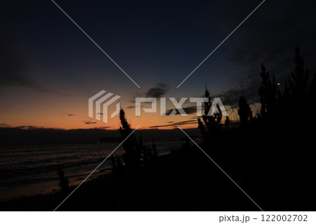 鎌倉・七里ヶ浜海岸から見る江ノ島とオレンジ色になる夕陽とのある風景 夕景 鎌倉・七里ヶ浜海岸から見る江ノ島とオレンジ色になる夕陽とのある風景 夕景 122002702