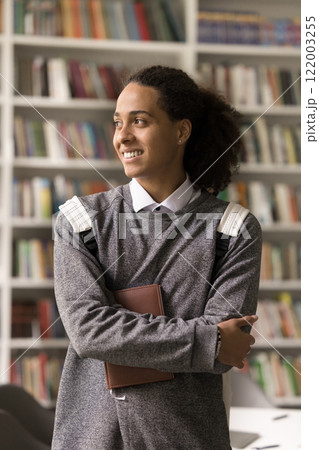 Young ethnic man student stand in library in dreamy pose Young ethnic man student stand in library in dreamy pose 122003255