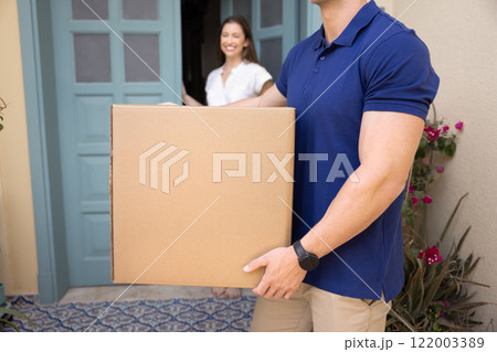 Strong male loader man carrying large package from female customer 122003389