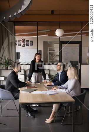 Businesspeople laughing, joking seated around table during presentation 122003411