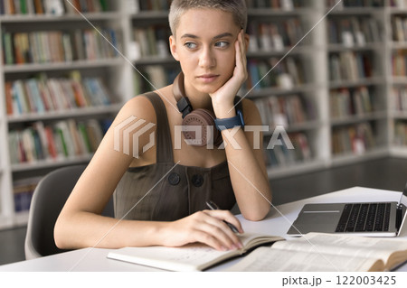 Pensive teen girl student study at library look aside think 122003425