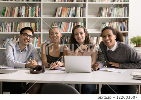 Portrait happy smart diverse students sitting by desk at library Portrait happy smart diverse students sitting by desk at library 122003607