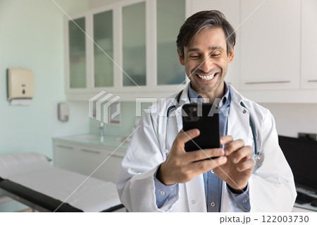 Cheerful male Hispanic doctor man chatting with patients 122003730