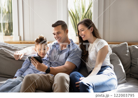 Couple of cheerful parents and kid watching funny online content Couple of cheerful parents and kid watching funny online content 122003795